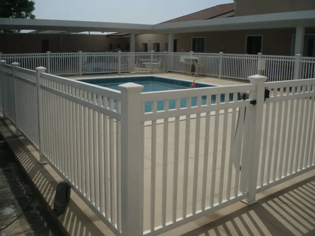 Vallado perimetral piscina con barandilla blanca rodeando zona de baño en patio residencial