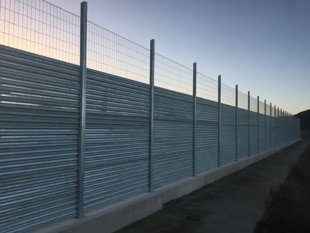 Vallado de proteccion metalico con chapa ondulada y malla superior instalado sobre murete